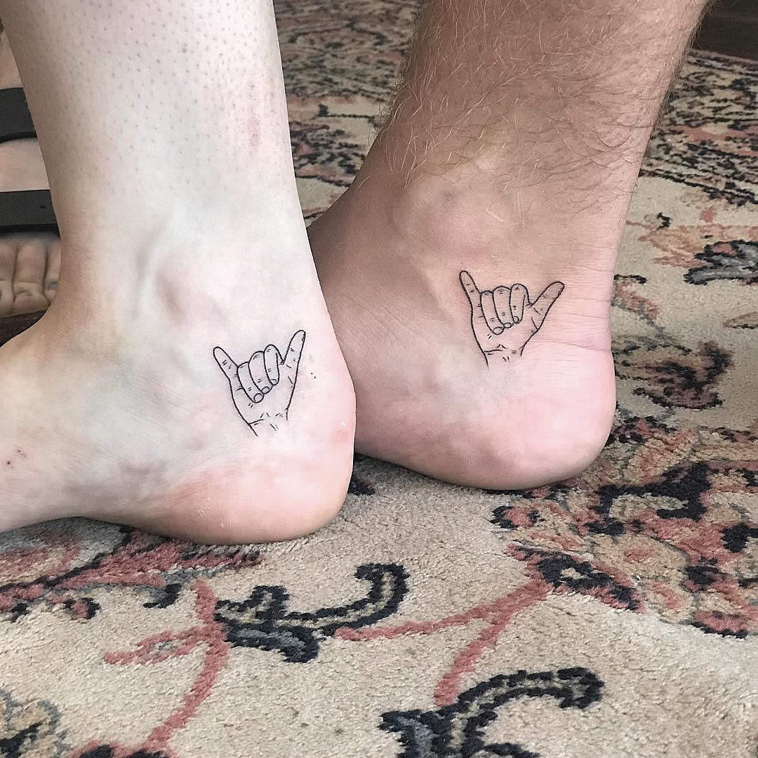 Matching tattoos of a hand gesture on two ankles